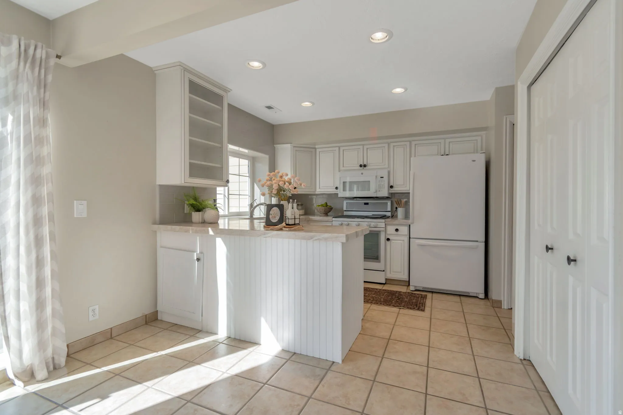 Kitchen featuring white cabinetry, light-toned countertops, recessed lighting, and tile flooring