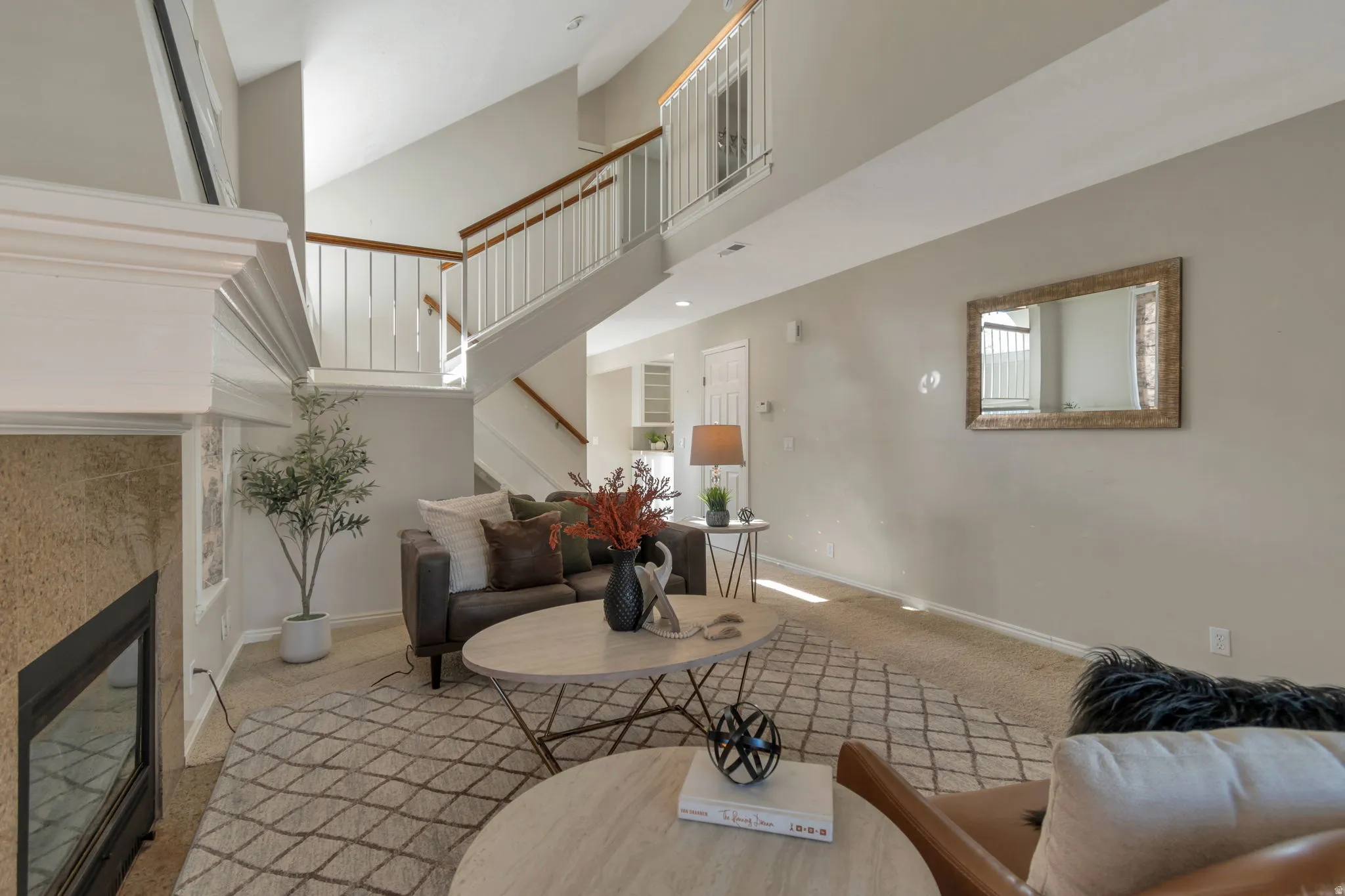 High vaulted ceilings, built-in fireplace, staircase with wood handrails, and a second-story landing with white railings