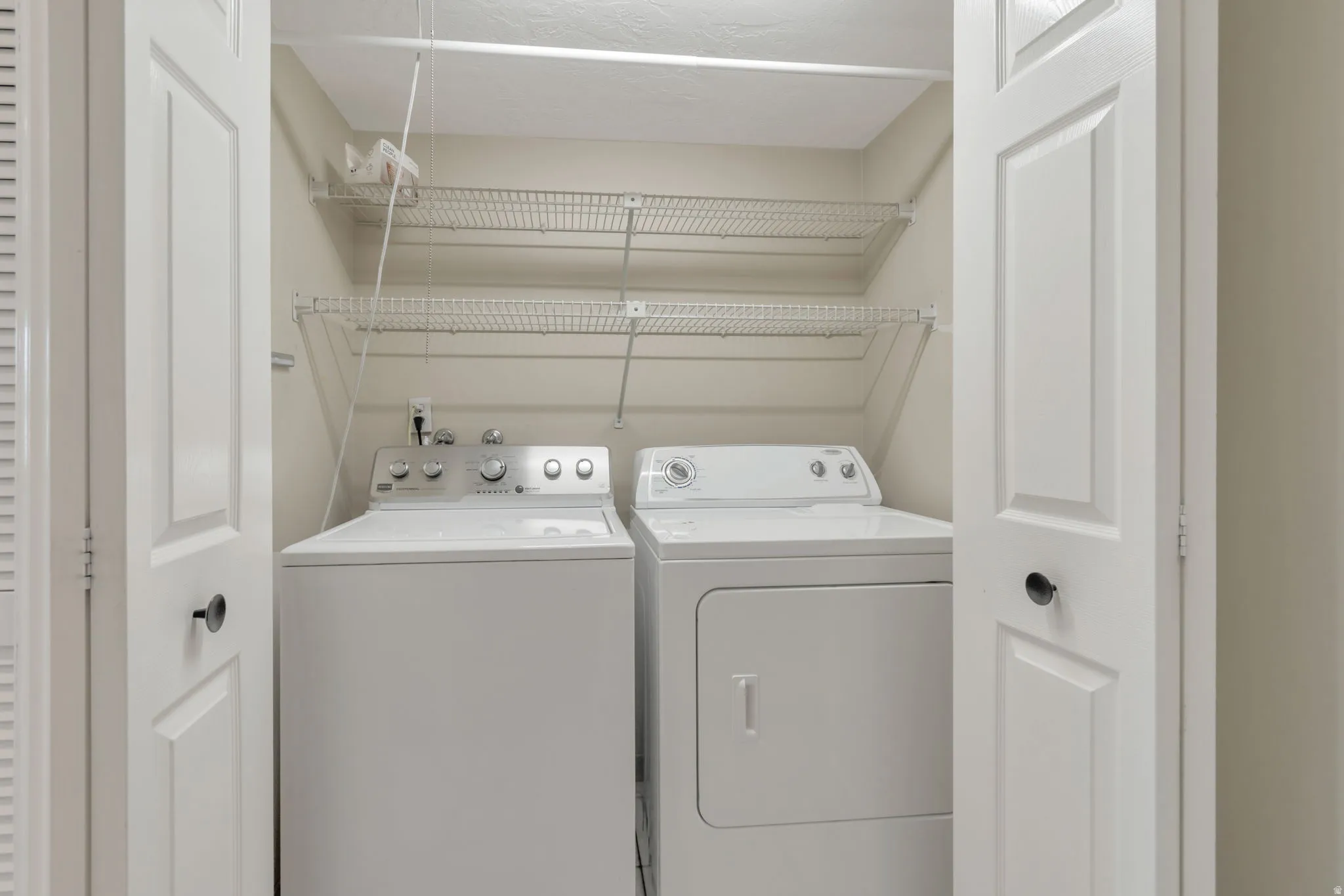 Laundry closet featuring a washer and dryer with wire shelving