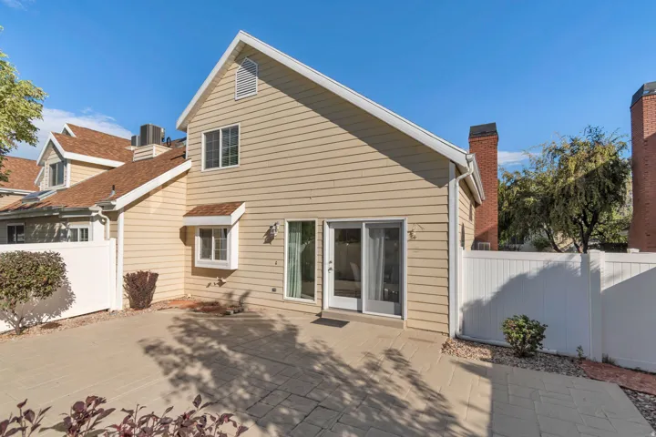 Paved patio area, siding exterior, dual-pane sliding glass door, white window frames, and private fencing