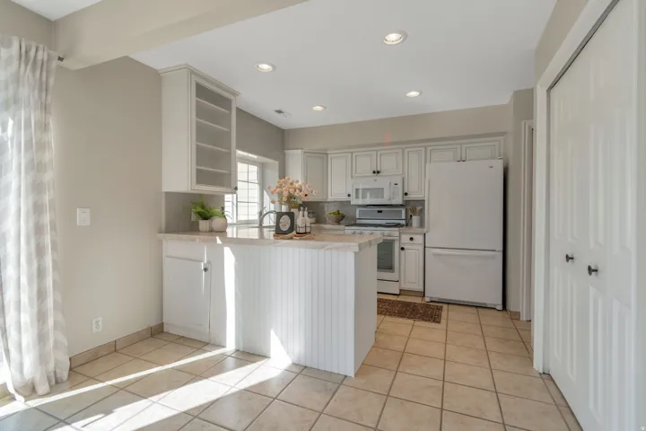 Kitchen featuring white cabinetry, light-toned countertops, recessed lighting, and tile flooring