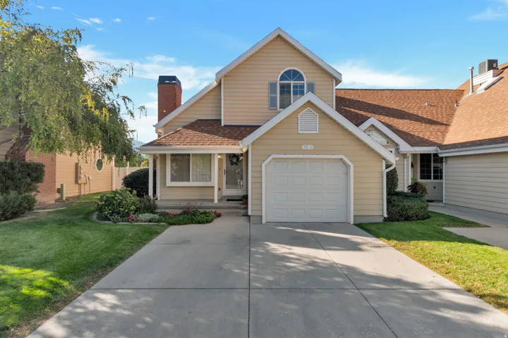 Two-story exterior with light-colored siding, a visible garage door, and a concrete driveway