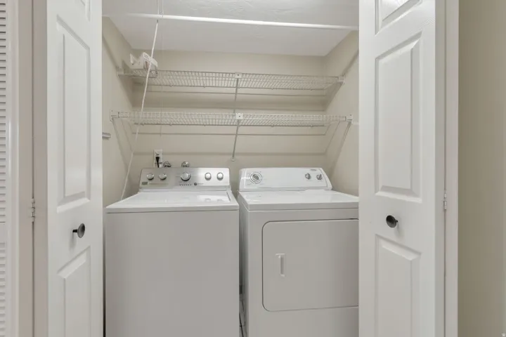 Laundry closet featuring a washer and dryer with wire shelving