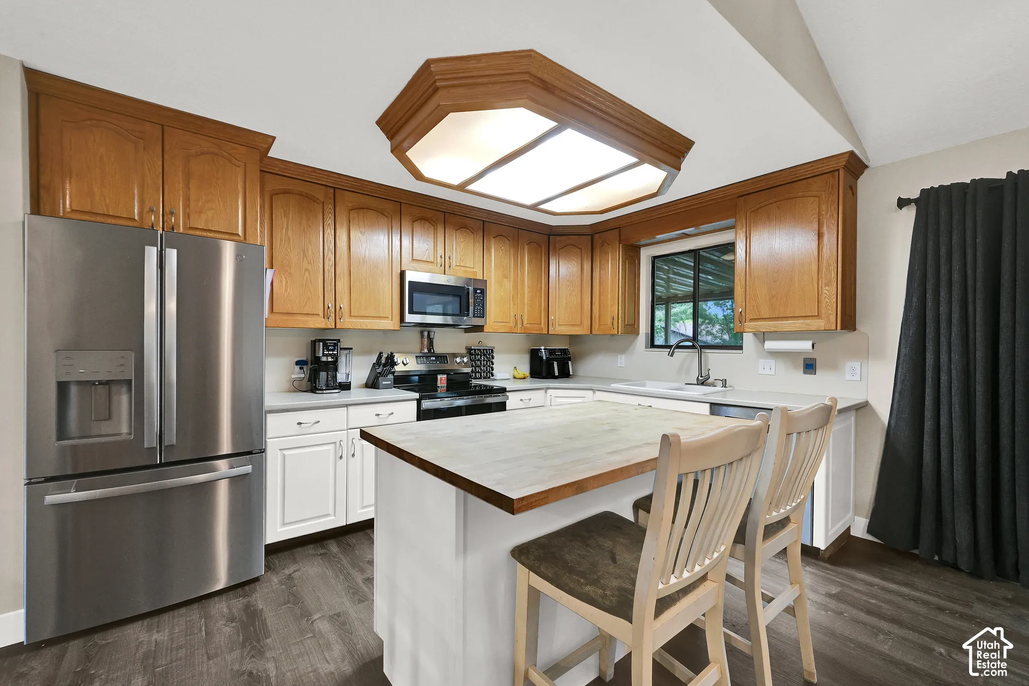 Kitchen featuring wood-finish cabinetry, stainless steel appliances, a center island with seating, and wood-finish flooring