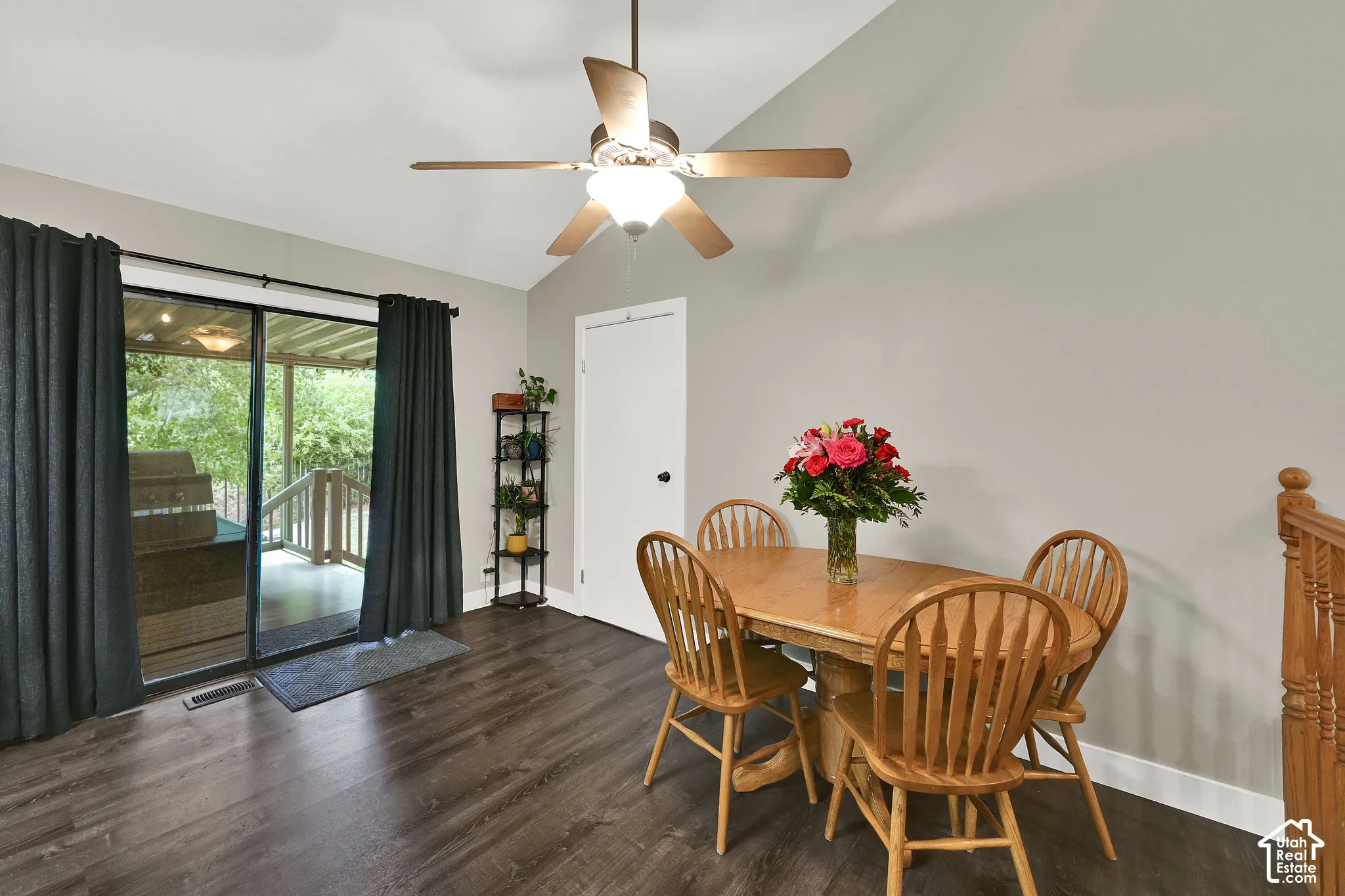 Vaulted ceiling with a ceiling fan, sliding glass door to an outdoor deck, wood-finish flooring, and a white interior door