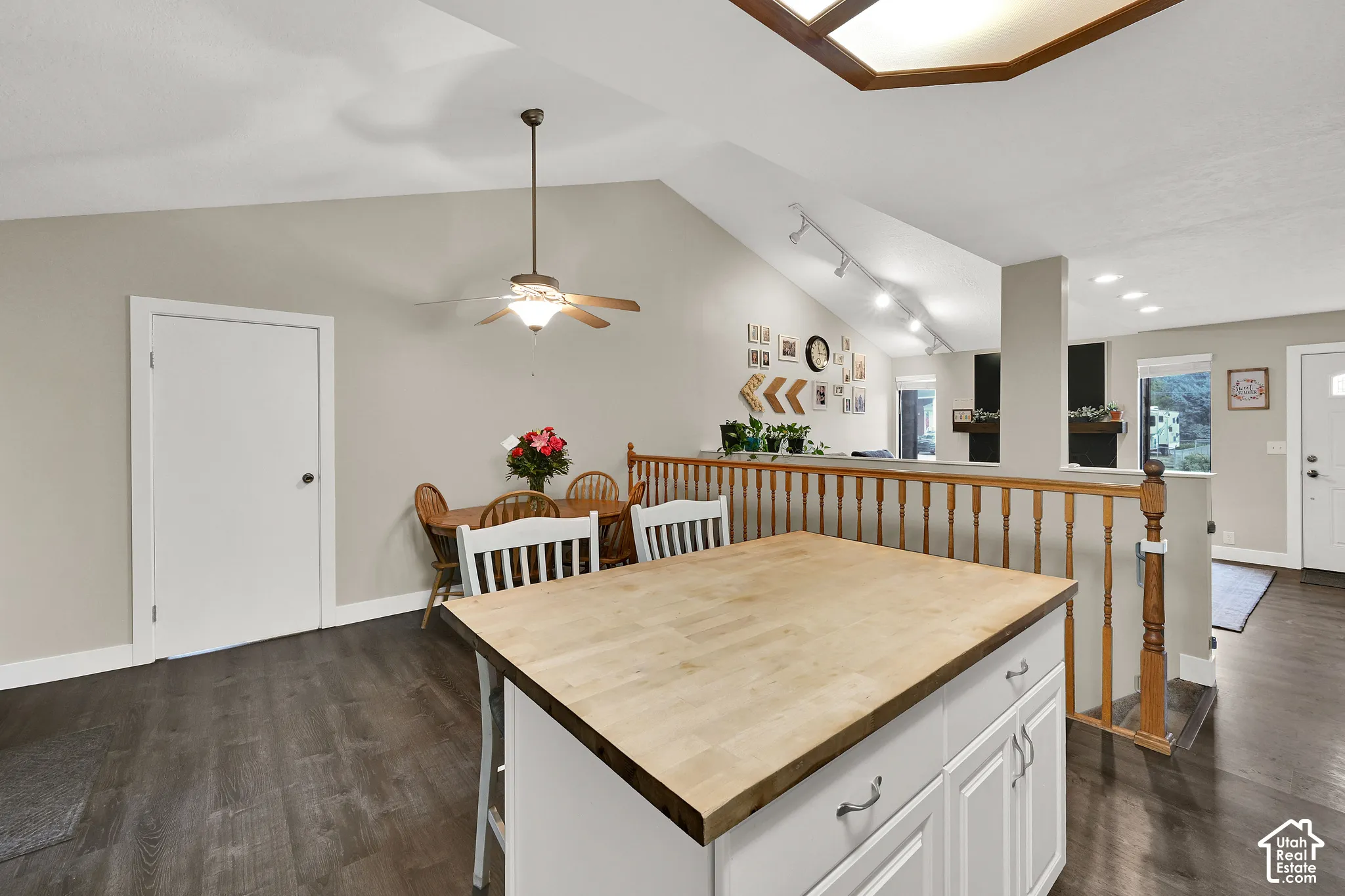 Kitchen island with wood-finish countertop, dark wood-finish flooring, vaulted ceiling, and skylight