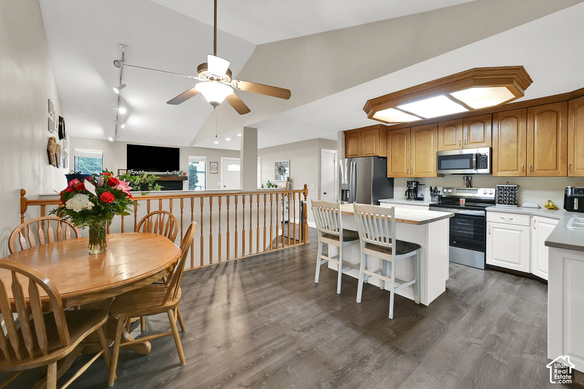 Vaulted ceilings with a ceiling fan, track lighting, and wood-finish flooring