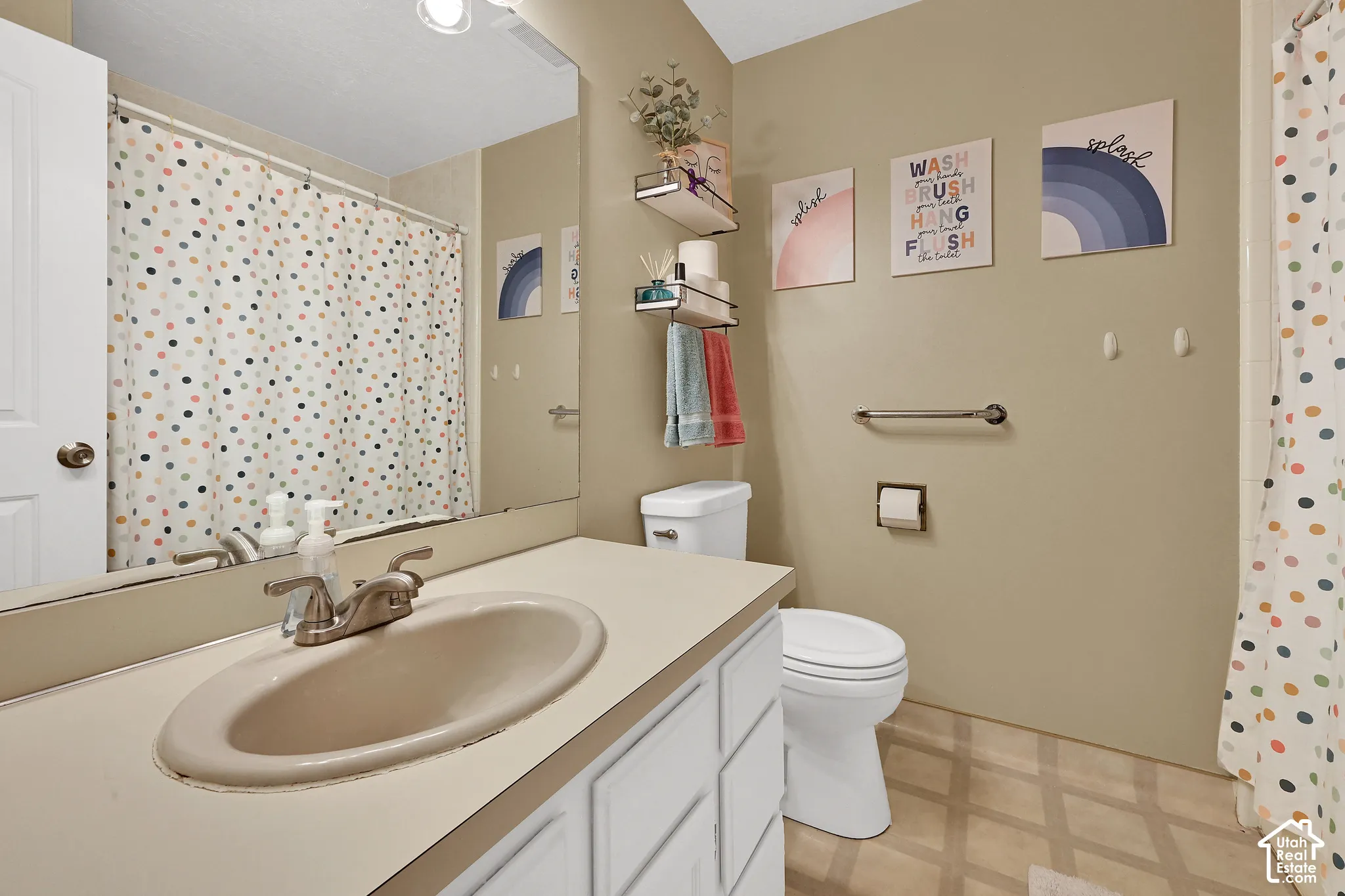 Bathroom with a vanity featuring an integrated sink, a toilet, and a full-width mirror