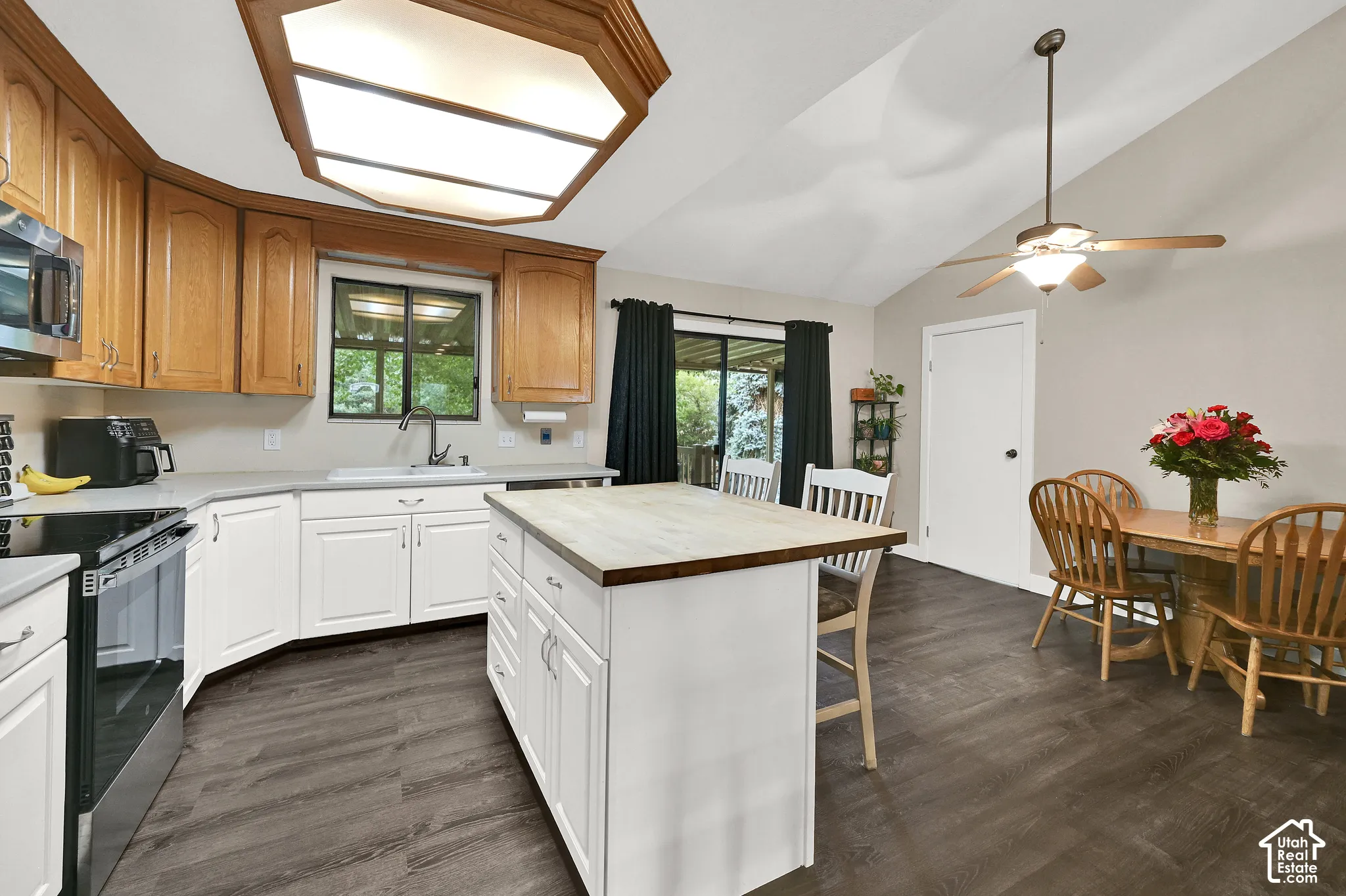 Kitchen featuring wood-finish flooring, white cabinetry, a central island, a vaulted ceiling, and sliding glass doors