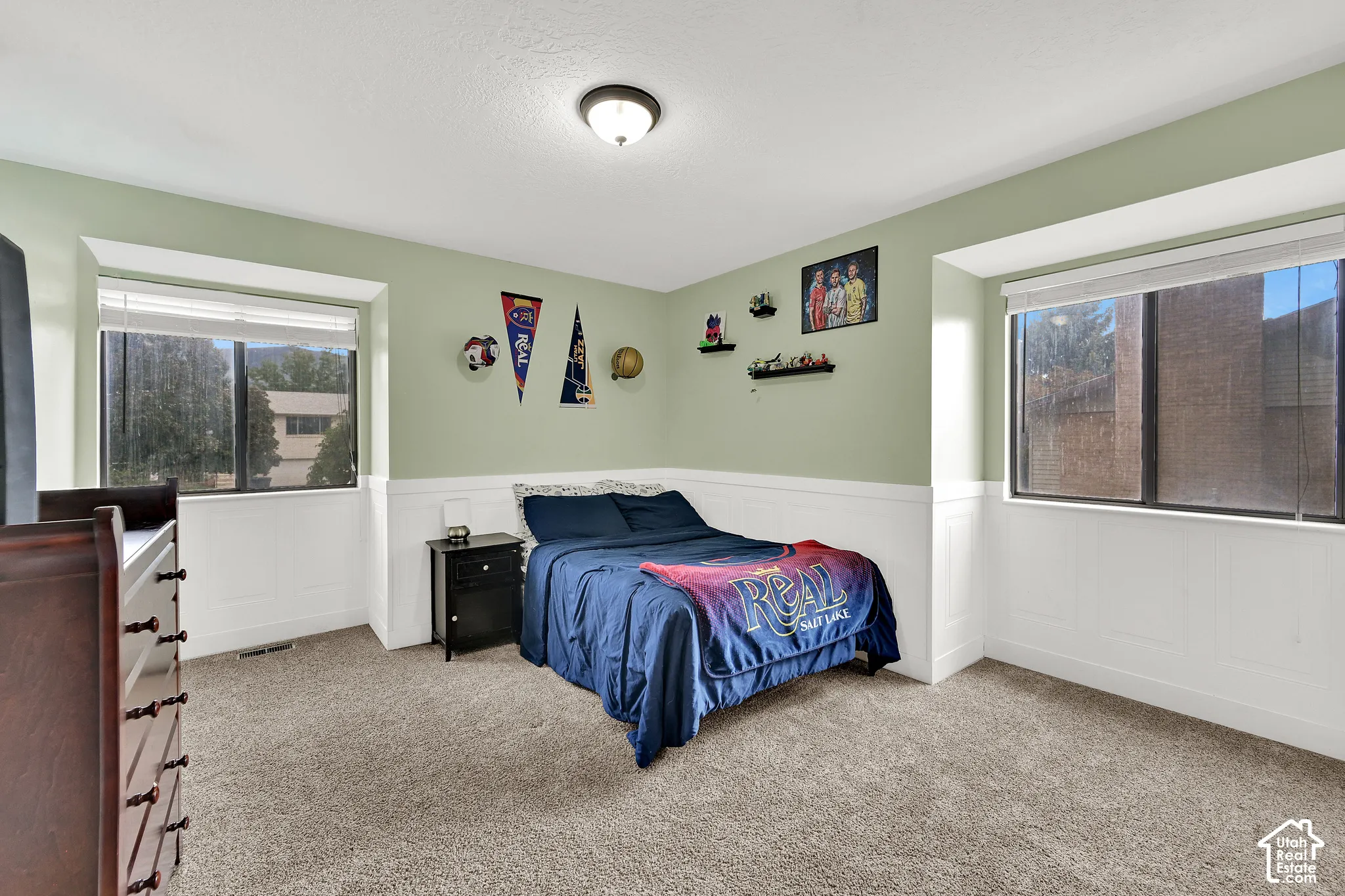 Neutral-toned carpeting, light green walls, and white wainscoting