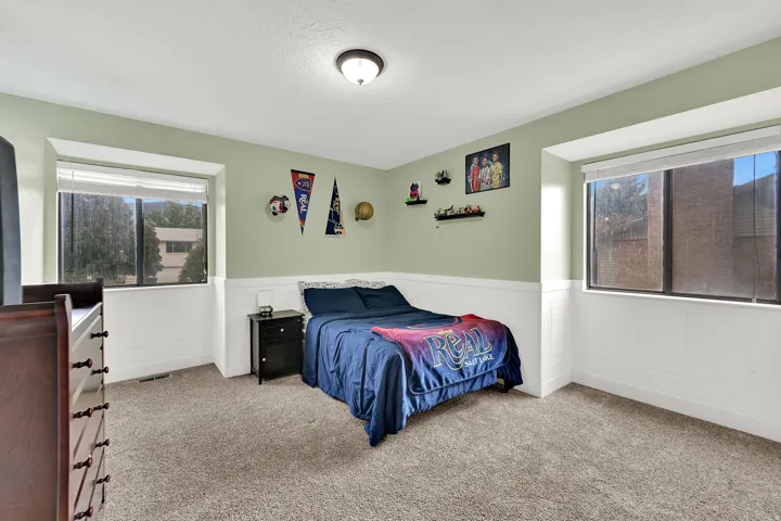 Neutral-toned carpeting, light green walls, and white wainscoting