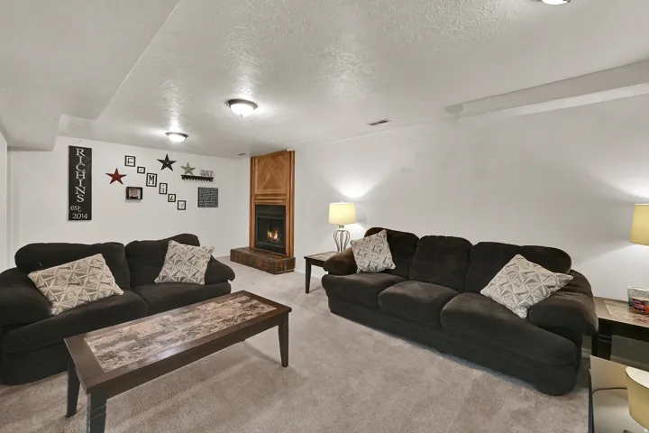 Carpeted living area featuring a fireplace with a wood-paneled surround and hearth, recessed lighting, and white walls