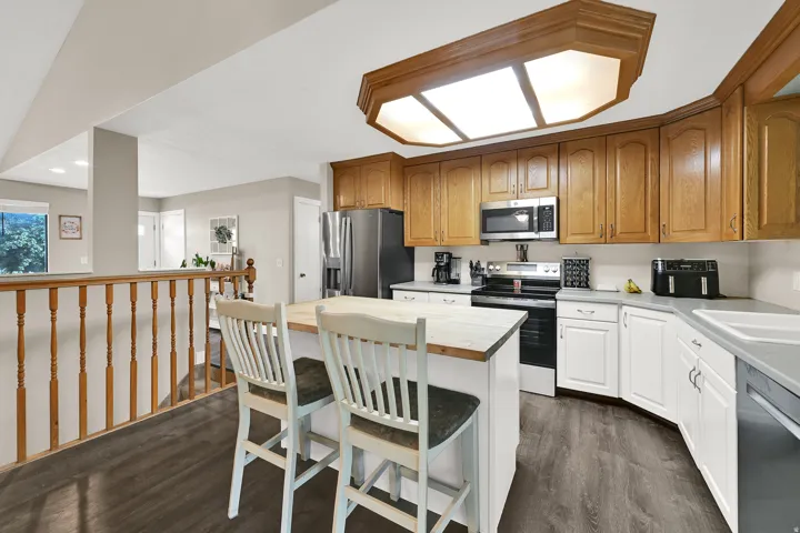 Kitchen featuring wood-finish flooring, wood cabinetry, white base cabinetry, and a center island with a wood countertop