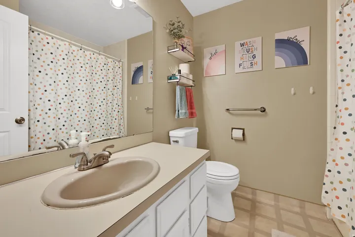 Bathroom with a vanity featuring an integrated sink, a toilet, and a full-width mirror