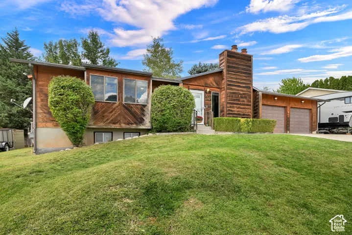 Wood-paneled facade with large windows, an integrated chimney structure, and a two-car garage