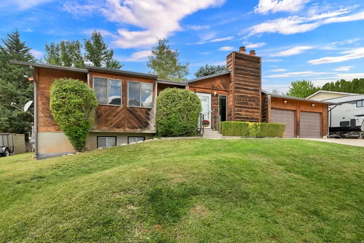 Wood-paneled facade with large windows, an integrated chimney structure, and a two-car garage