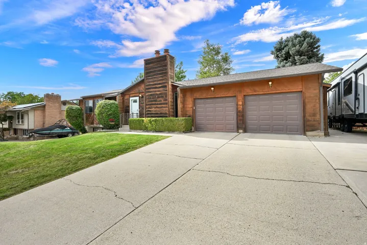 Two-car garage with panel doors, wood-clad exterior, and a concrete driveway