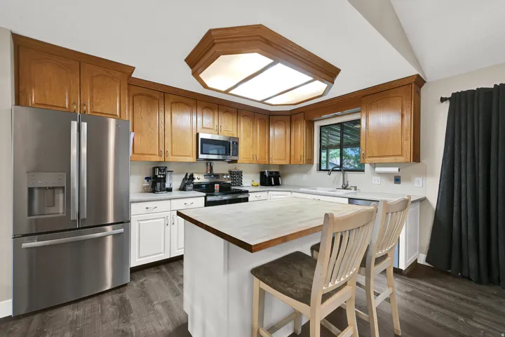Kitchen featuring wood-finish cabinetry, stainless steel appliances, a center island with seating, and wood-finish flooring
