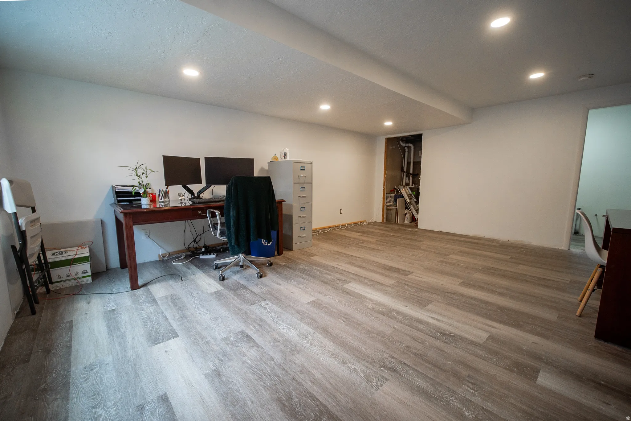 Spacious finished basement living area featuring durable wood-look flooring, recessed lighting, and an open layout that offers endless possibilities for a family room, extra bedroom, recreation space, home office, or fitness area.