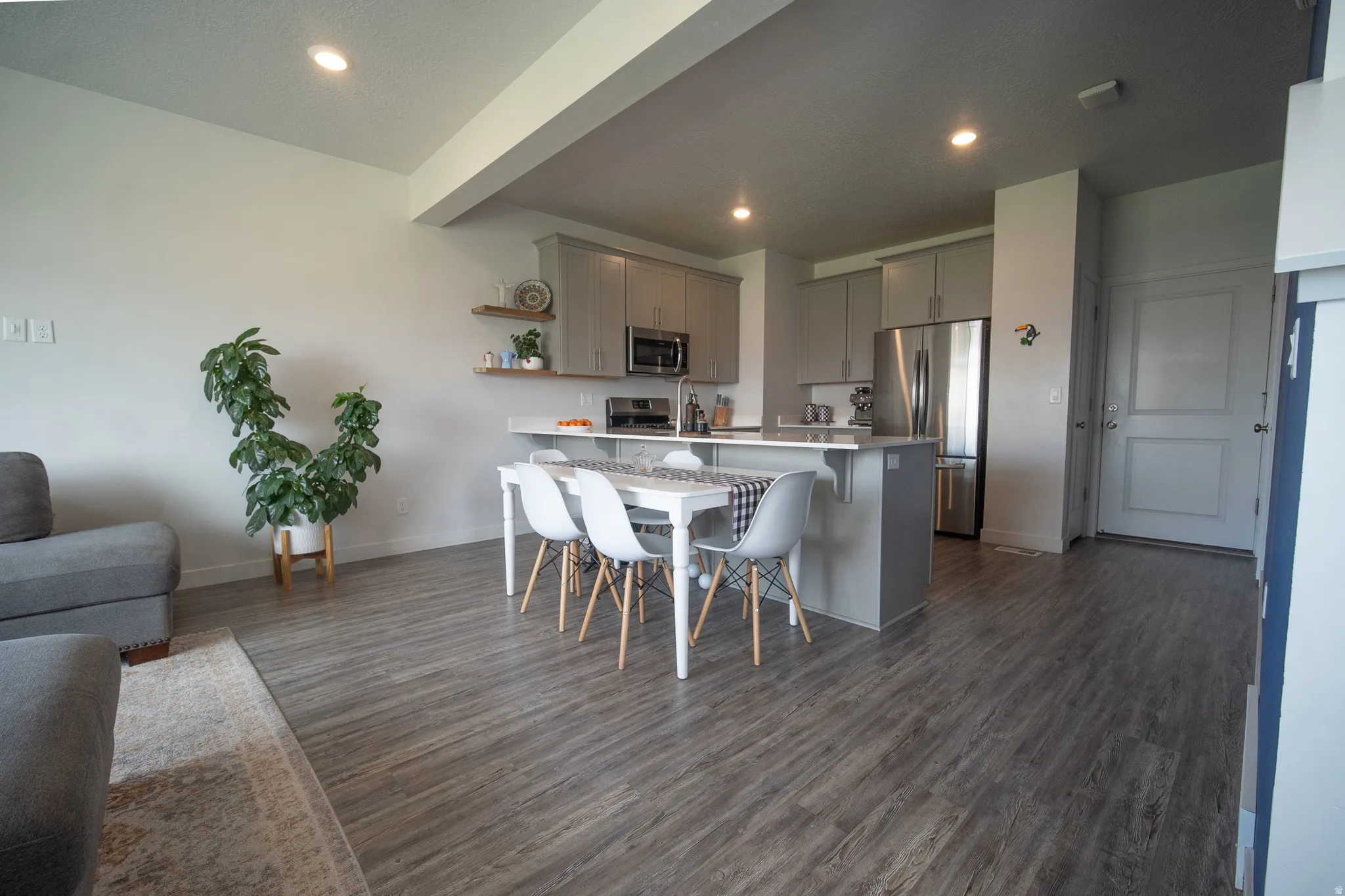 Open-concept kitchen with stainless steel  appliances, gray cabinetry, a spacious island, and seamless flow into the dining area for everyday living and gatherings