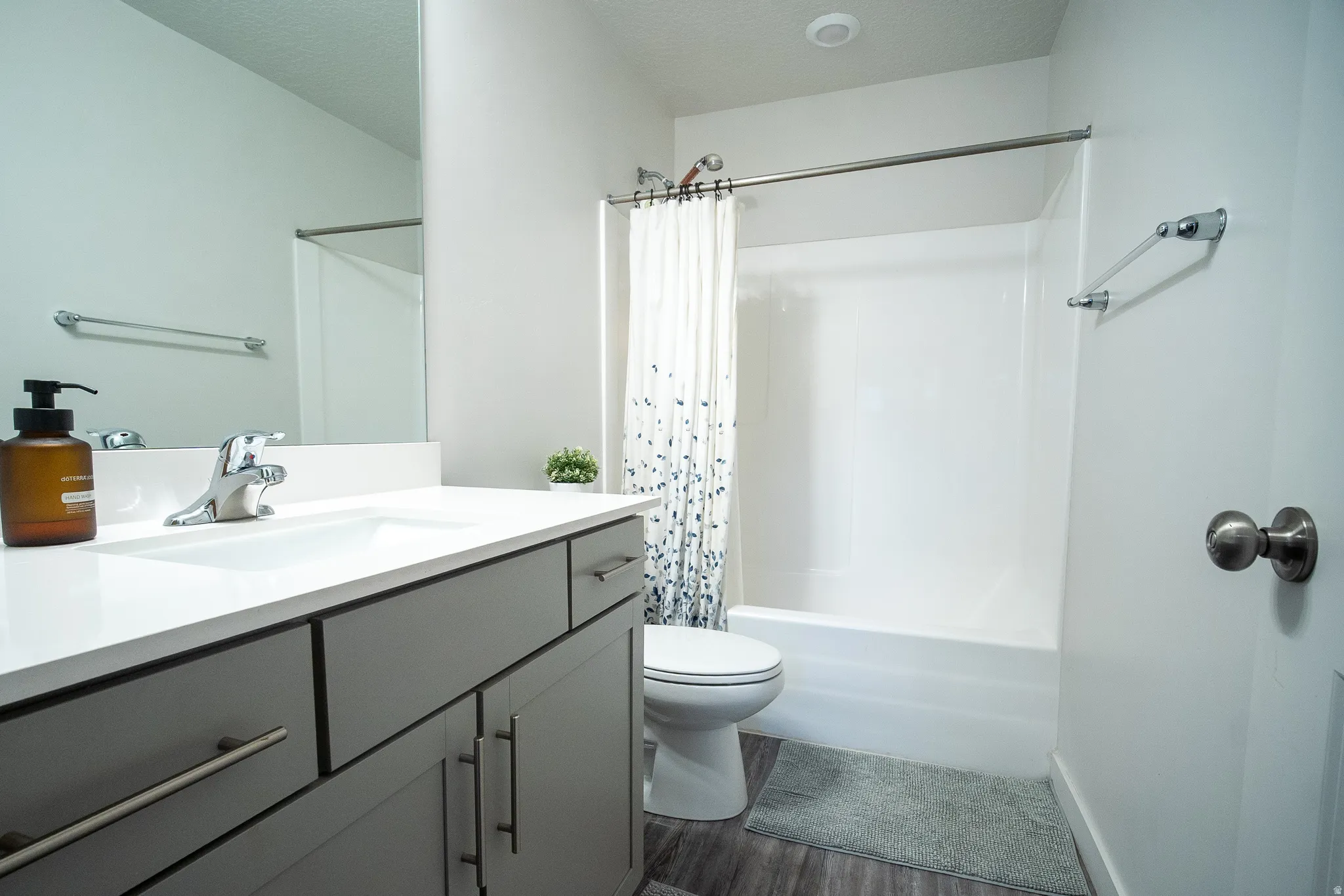 Stylish full bathroom featuring a modern gray vanity with ample storage, a solid-surface countertop, contemporary fixtures, and a tub/shower combination designed for both comfort and convenience.