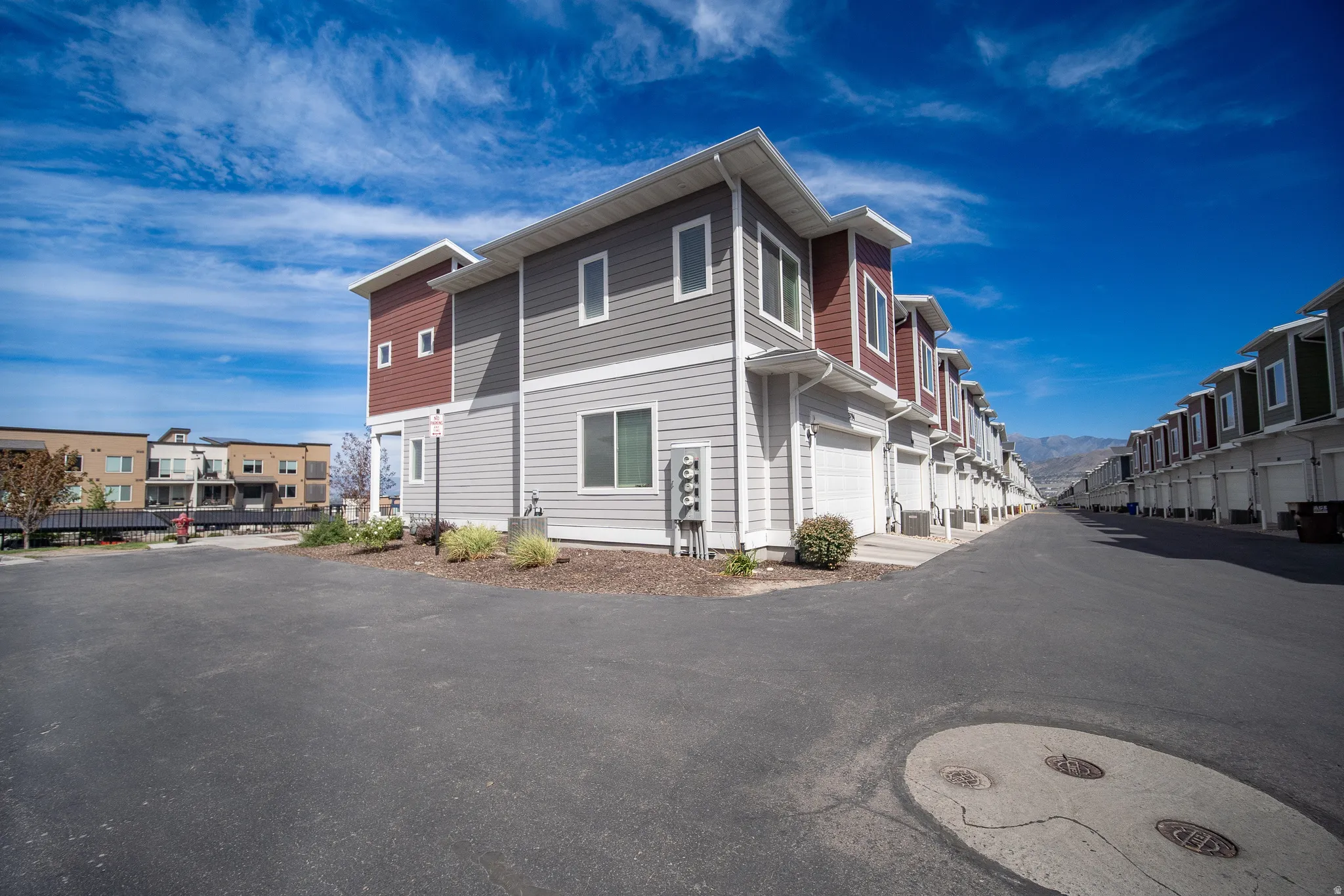 Multi-level residential exterior with mixed siding, attached garage, and multiple windows