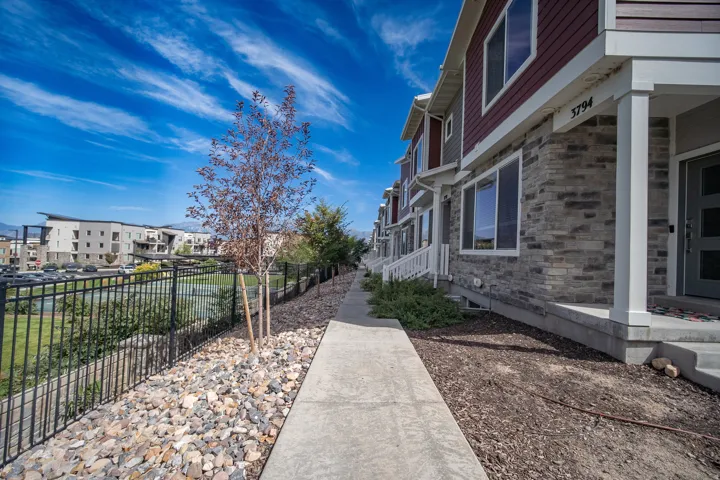Contemporary multi-level townhome featuring a stone and siding exterior, white trim accents, and a covered entry