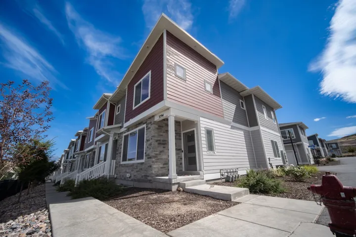 Contemporary townhome with attractive curb appeal featuring a modern exterior with stone veneer, horizontal siding accents, large windows, and a welcoming walkway leading to the entrance.