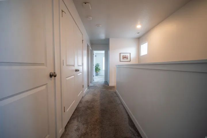 Carpeted hallway featuring white panel doors, recessed lighting, and a partial wall with trim detail