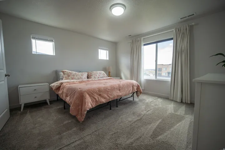 Bright and inviting, the spacious master bedroom is filled with abundant natural light and features neutral paint tones, plush carpeting, and stylish flush-mount ceiling lighting. The warm, timeless finishes create a peaceful and comfortable retreat with