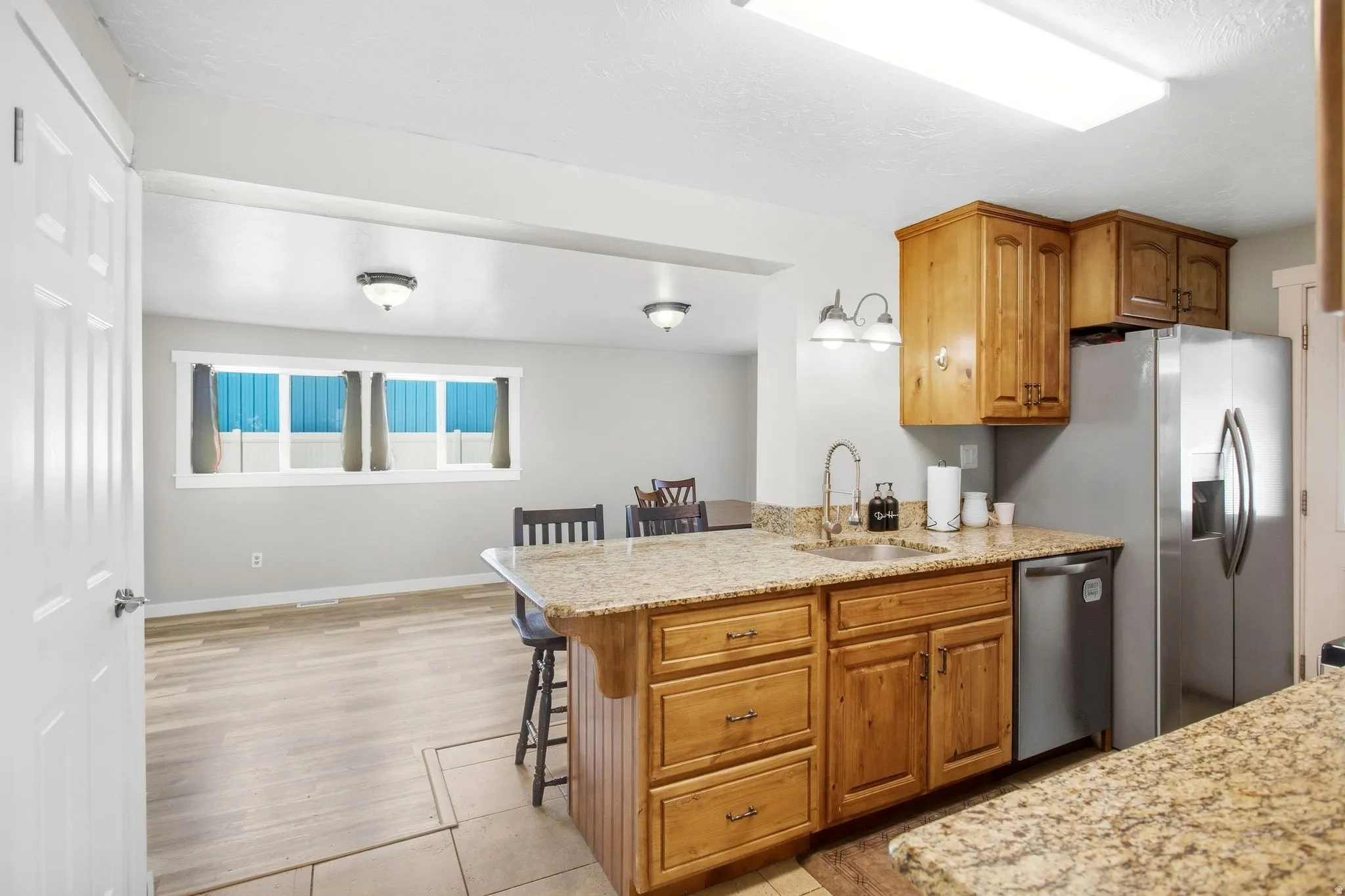 Kitchen featuring wood-finish cabinetry, stainless steel appliances, and stone-finish countertops with an integrated sink