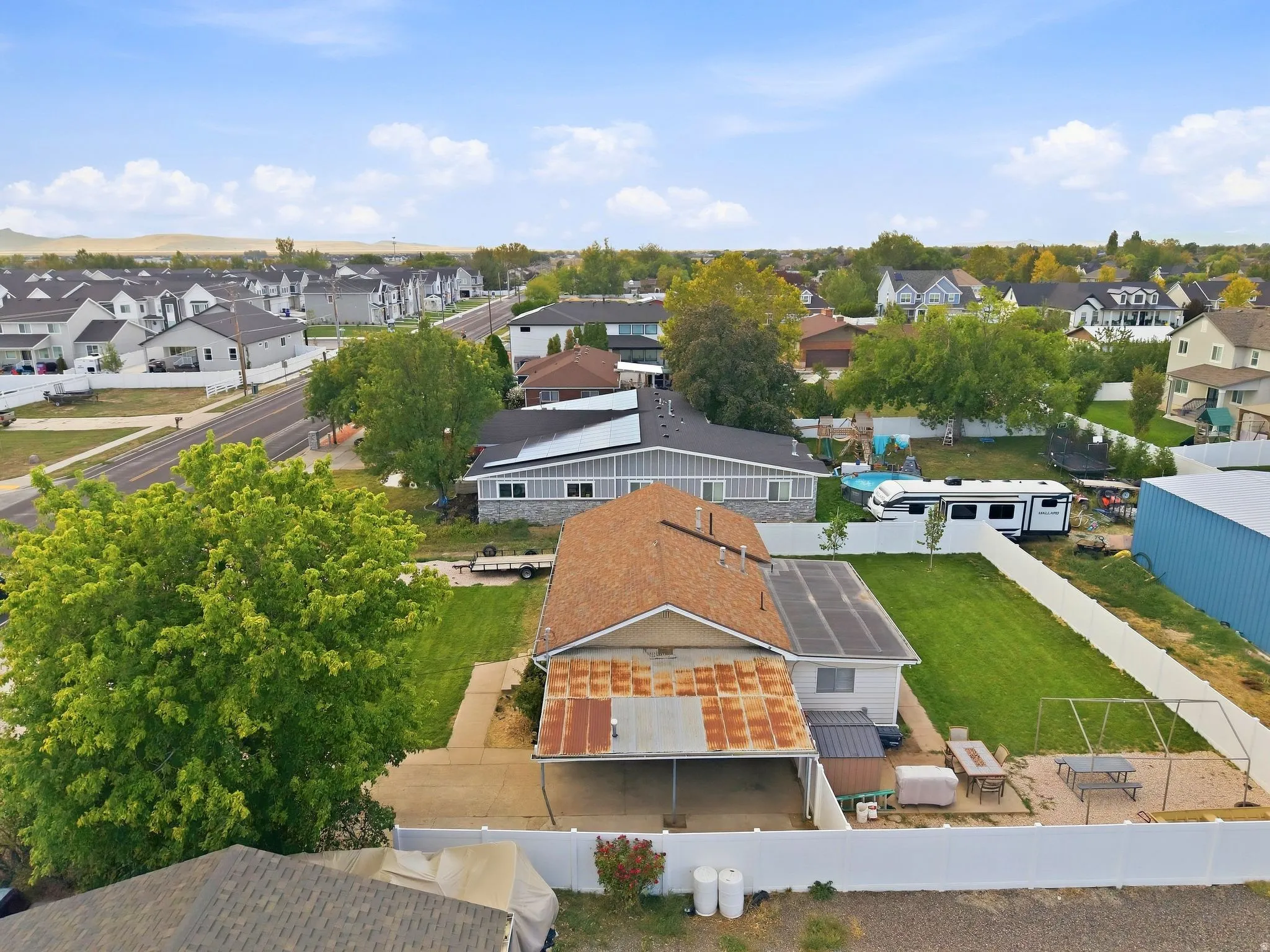 Expansive lot featuring a large grassy area, privacy fencing, and a detached carport