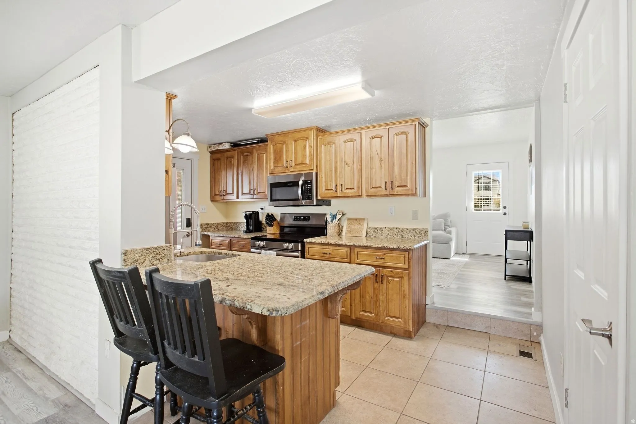Kitchen featuring wood cabinetry, integrated stainless steel appliances, and granite countertops