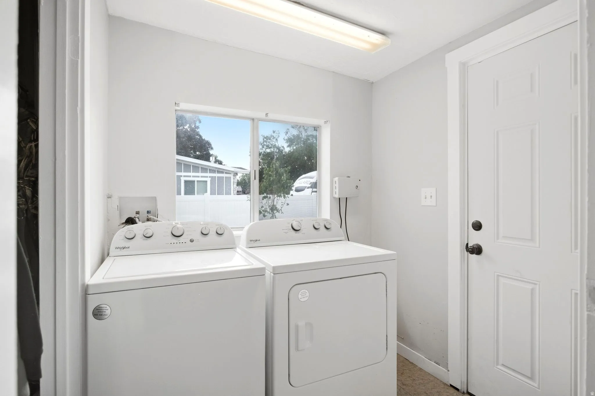 Laundry area with a window, white walls, and a fluorescent ceiling light