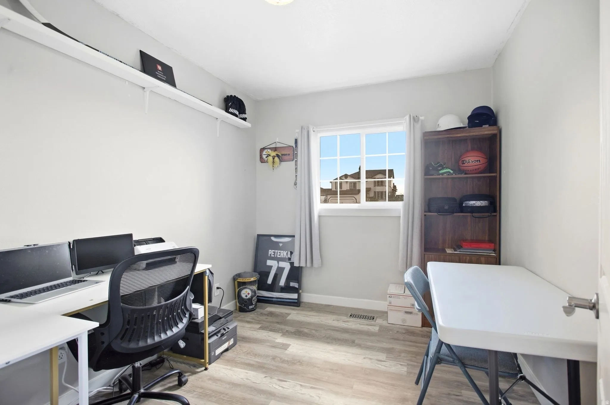 Light-toned walls with wood-finish flooring, a white-framed window, and a built-in shelf