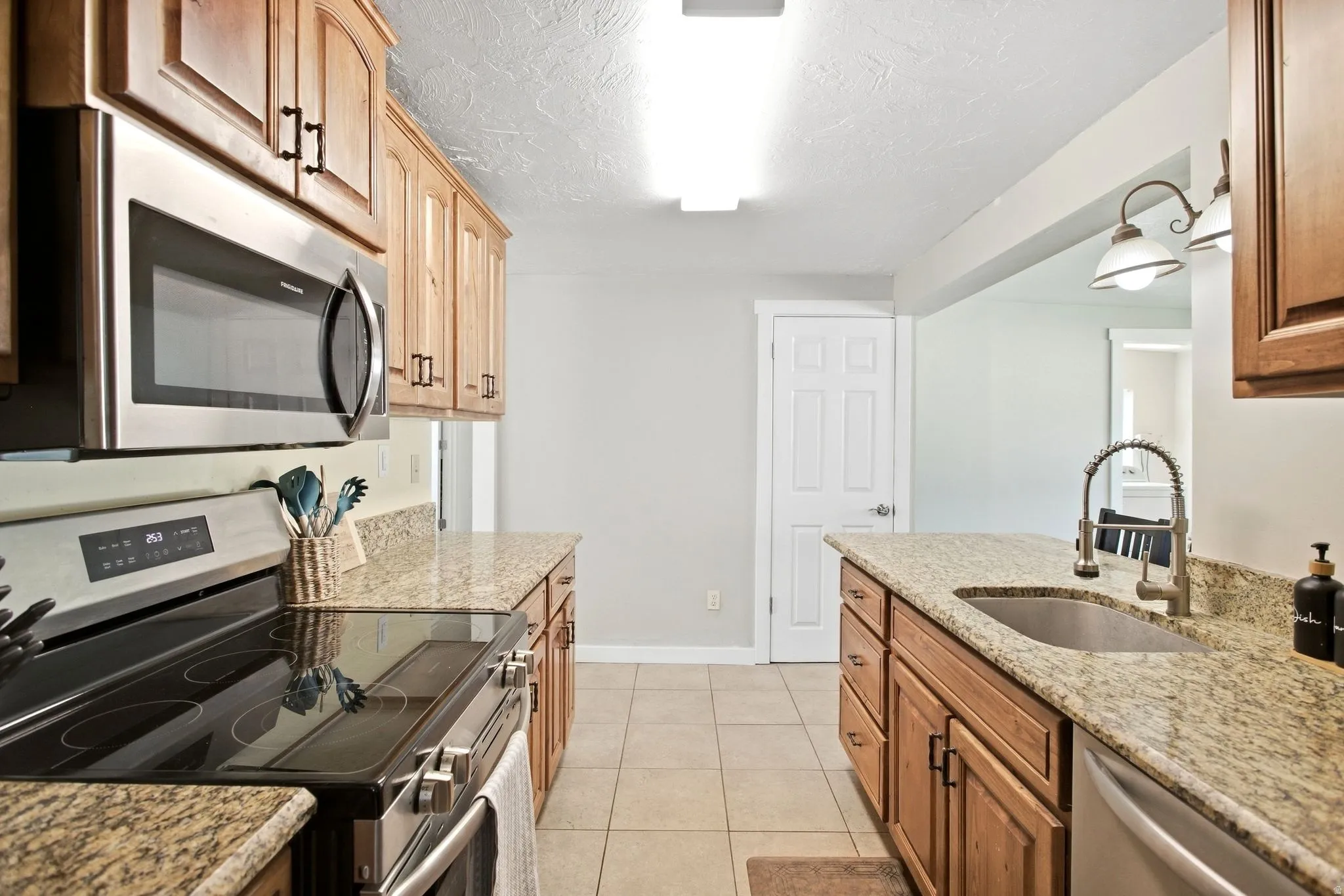 Kitchen featuring wood cabinetry, granite countertops, stainless steel appliances, and tile flooring
