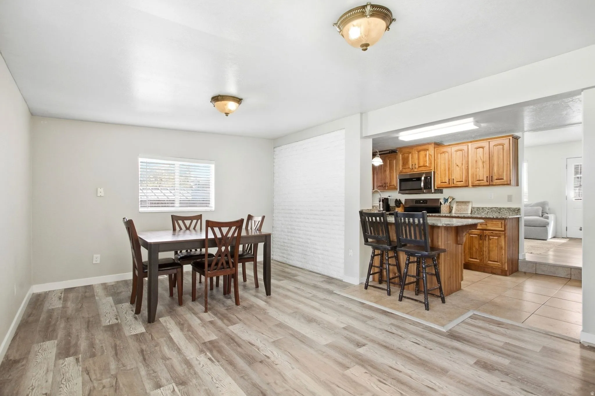 Wood-finish flooring throughout the dining area, featuring a white painted brick accent wall