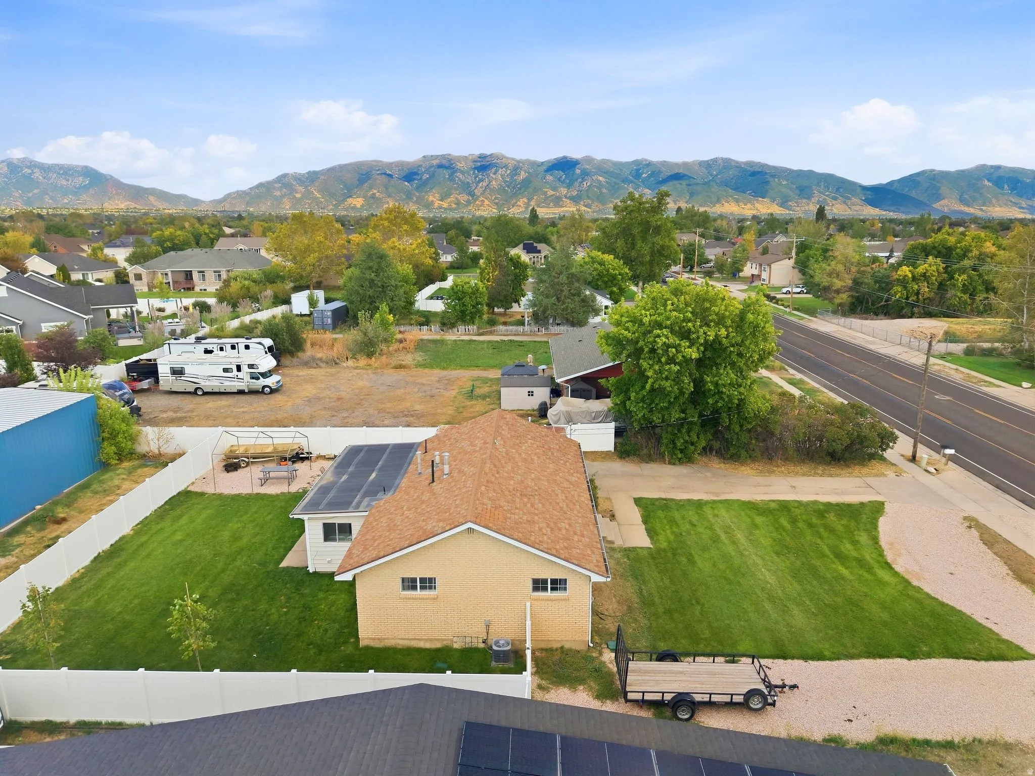 Property featuring a fenced backyard with a manicured lawn, solar panels, and a concrete patio