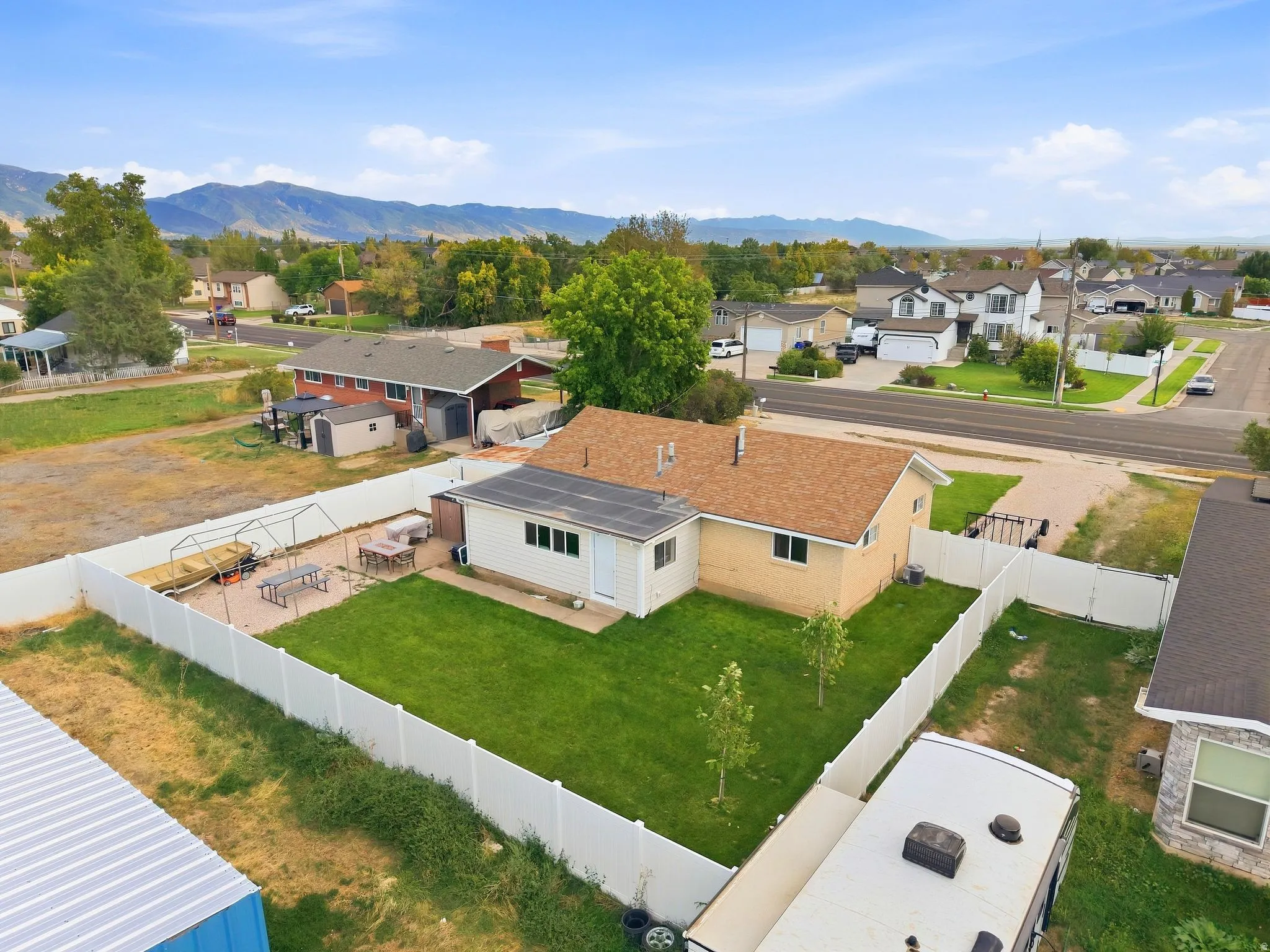 Fenced backyard featuring a manicured lawn, paver patio, and mountain backdrop