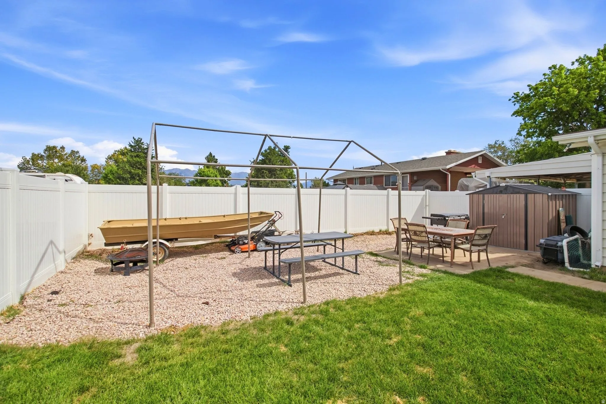 Expansive backyard featuring a manicured lawn, a gravel area, and a paved patio space