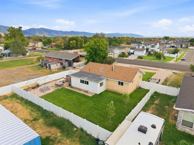 Fenced backyard featuring a manicured lawn, paver patio, and mountain backdrop