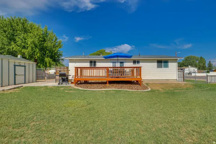 Expansive backyard with a manicured lawn, wood deck, and a detached storage shed