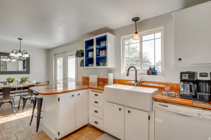 Kitchen featuring a double basin farmhouse sink, wood-finish countertops, white cabinetry, and tile flooring
