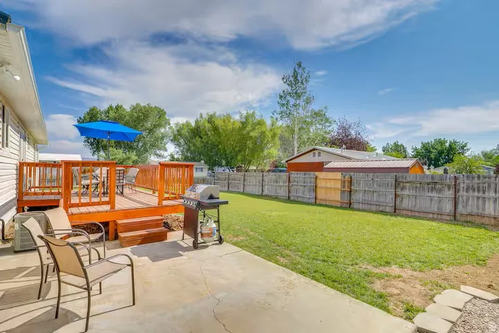 Spacious backyard featuring a wood deck with railings, concrete patio, expansive lawn, and wood privacy fencing