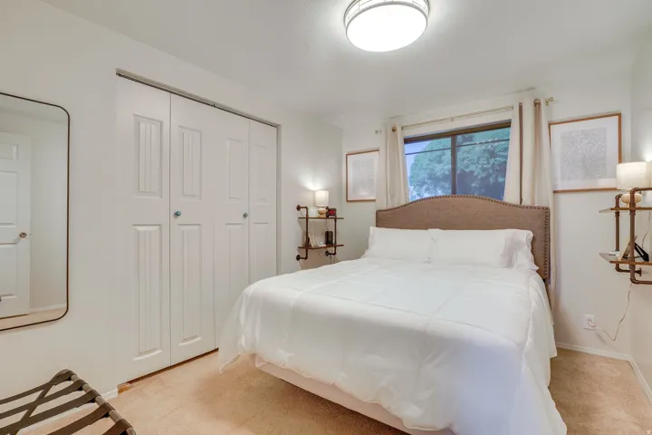 Recessed window with drapes, flush-mount ceiling light, paneled closet doors, and light-toned carpet