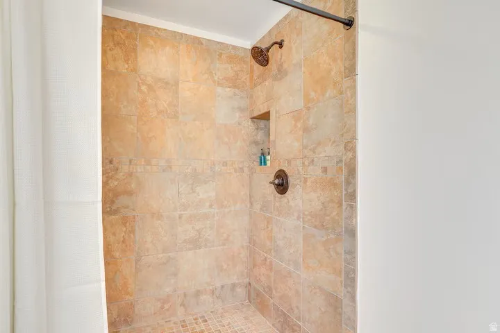 Tiled shower with a mosaic tile floor, recessed niche, and dark bronze fixtures