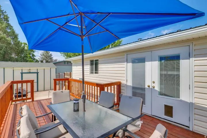 Expansive wood deck with wood railings, double French patio doors, exterior siding, and a detached storage shed