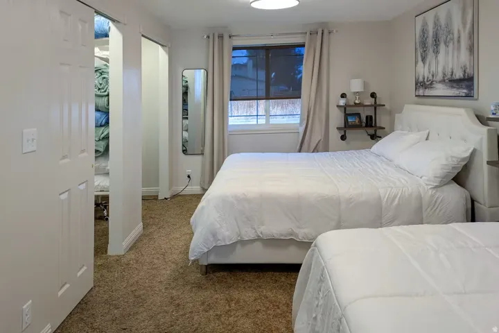 Neutral wall color, carpet flooring, window with drapes, and a built-in closet with a sliding door