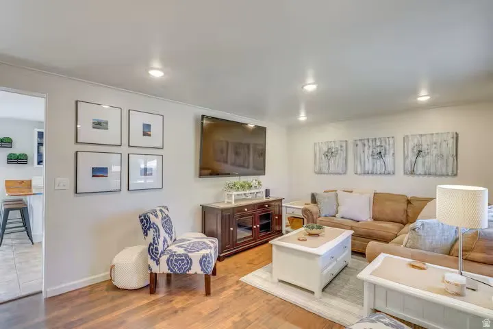Recessed ceiling lighting, wood-finish flooring, light-toned walls, built-in media console, and an open doorway