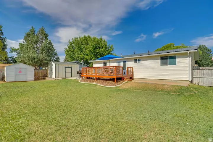 Wood deck with railings, two storage sheds, and mature landscaping